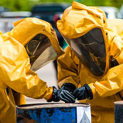 Dos trabajadores de respuesta a emergencias con trajes de protección contra materiales peligrosos trabajando para contener radiación