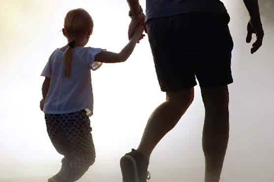 a young girl holding hands with her father