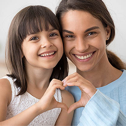 a young girl and her mother holding hands in the shape of a heart
